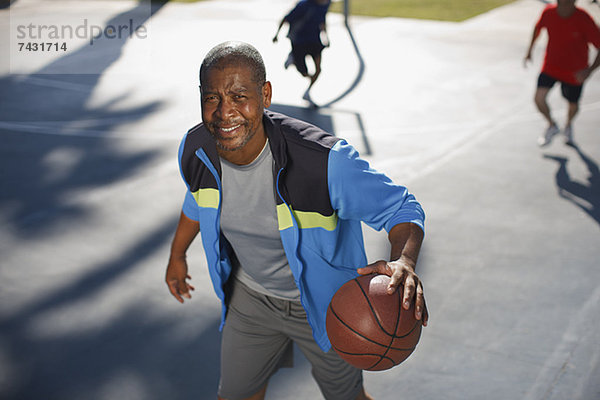 Älterer Mann spielt Basketball auf dem Platz