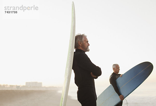Ältere Surfer  die sich am Strand an Bord lehnen