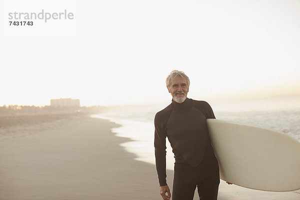 Ältere Surfer mit Brett am Strand