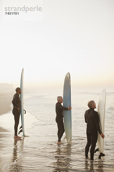 Ältere Surfer mit Brettern am Strand