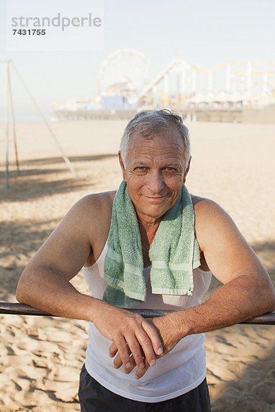 Älterer Mann entspannt sich nach dem Training am Strand