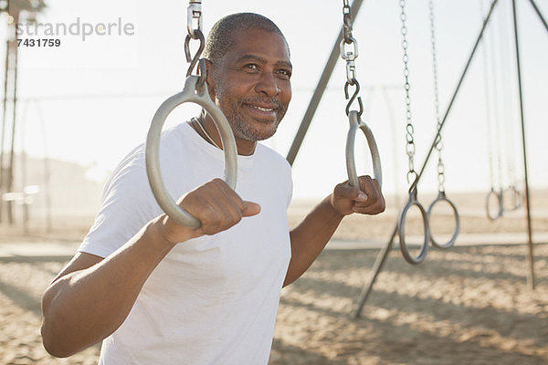 Älterer Mann mit Trainingsringen am Strand