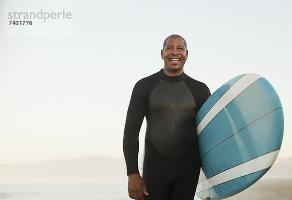 Ältere Surfer mit Brett am Strand