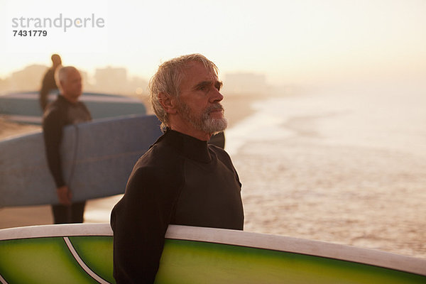 Ältere Surfer mit Brettern am Strand