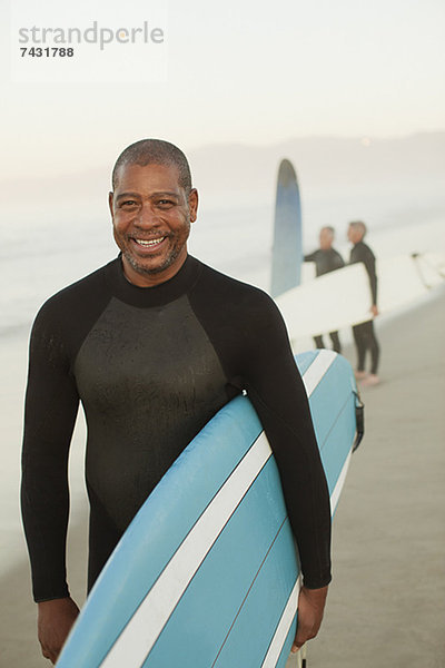 Ältere Surfer mit Brett am Strand