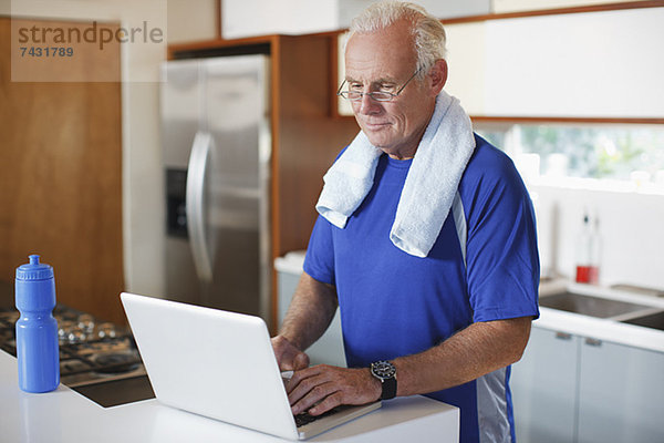 Älterer Mann mit Laptop nach dem Training