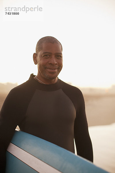 Ältere Surfer mit Brett am Strand