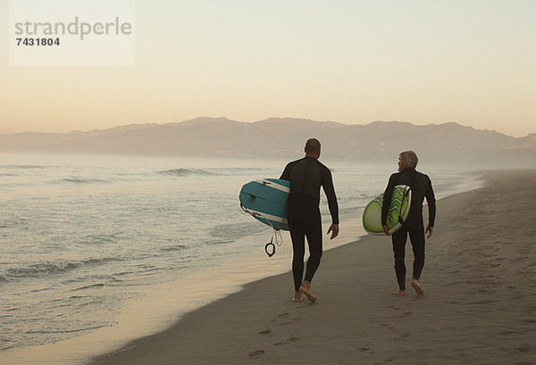 Ältere Surfer mit Brettern am Strand