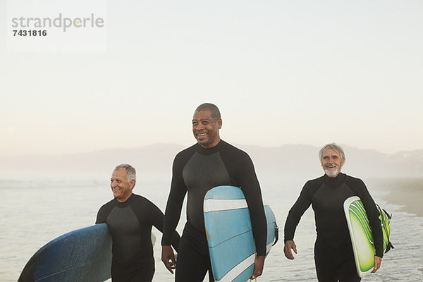 Ältere Surfer mit Brettern am Strand