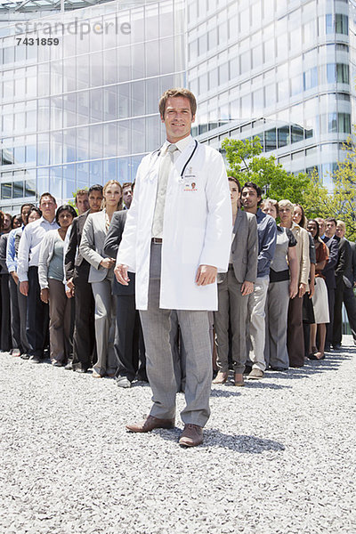 Porträt eines lächelnden Arztes mit Geschäftsleuten im Hintergrund