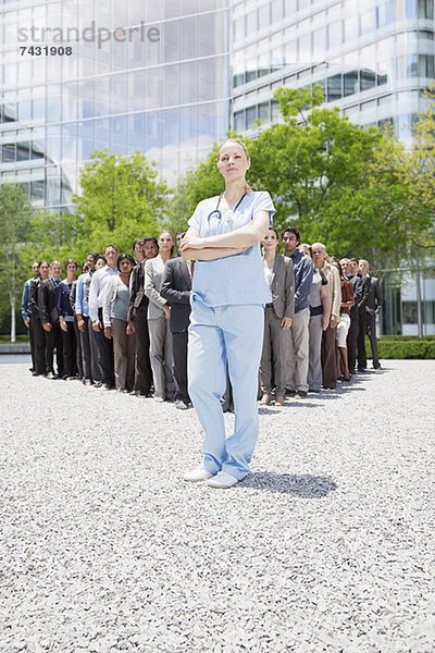 Porträt einer selbstbewussten Krankenschwester mit Geschäftsleuten im Hintergrund