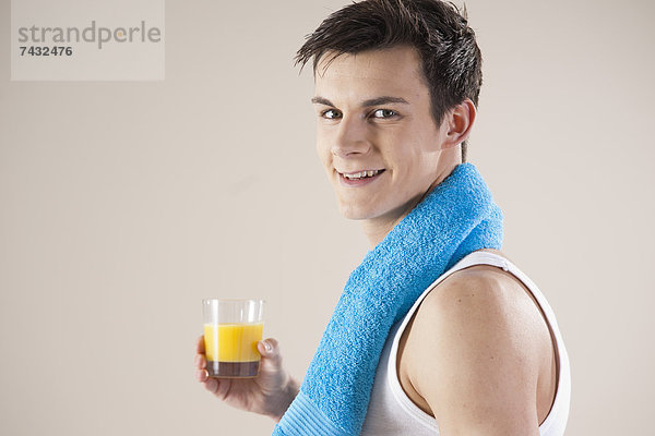 junger lachender Mann mit einem Glas Orangensaft