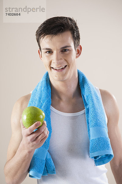 lachender junger Mann mit einem Apfel
