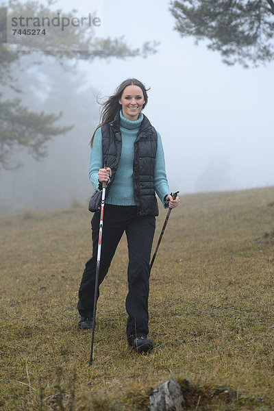 Brünette junge Frau macht Nordic Walking