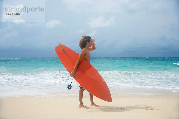 Mann mit Surfbrett am tropischen Strand