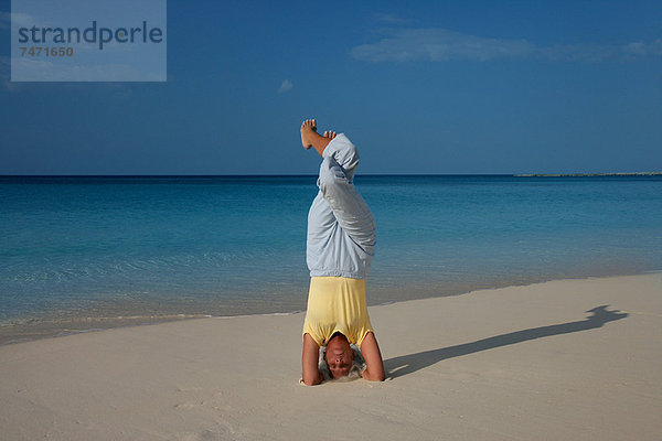 Frau praktiziert Yoga am tropischen Strand