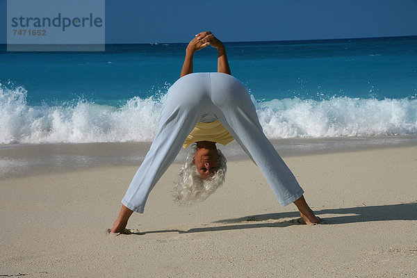 Frau praktiziert Yoga am tropischen Strand