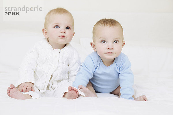 Babys sitzen zusammen auf dem Sofa