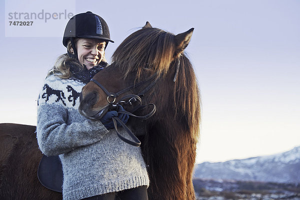 Frau lächelt mit Pferd im Freien