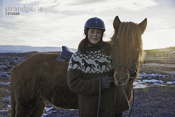 Frau lächelt mit Pferd im Freien
