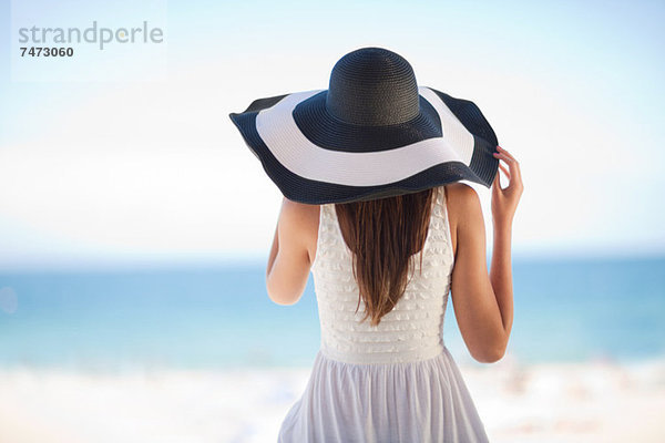 Frau mit Schlapphut am Strand