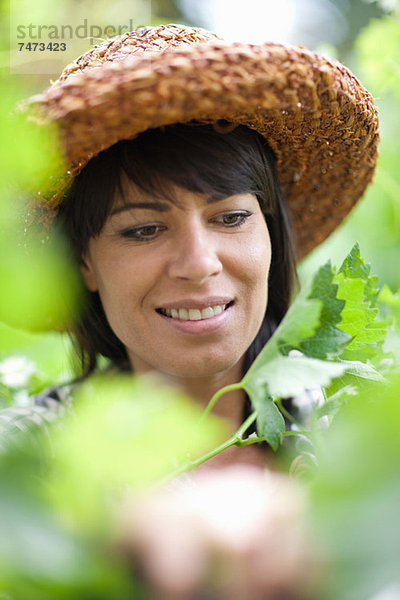 Lächelnde Frau in hohen Pflanzen stehend