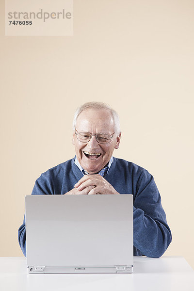 sitzend  Senior  Senioren  Mann  Computer  Notebook  sehen  lachen  Tisch