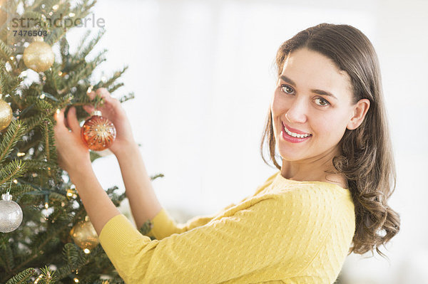 Frau schmückt Weihnachtsbaum