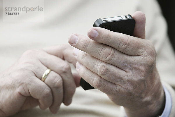 Senior hält Smartphone in den Händen