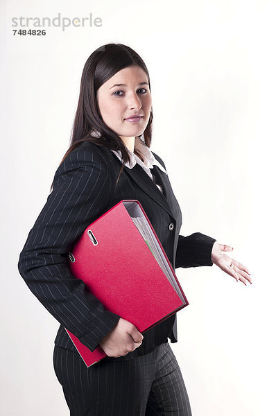 Geschäftsfrau mit rotem Aktenordner unter dem Arm in fragender Haltung