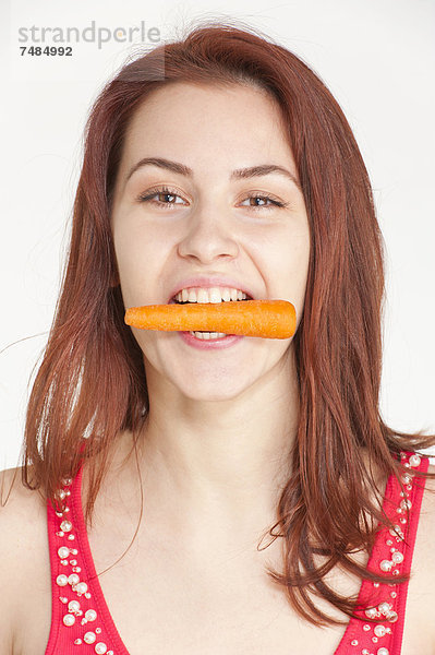 Junge Frau beisst auf eine Bio-Karotte