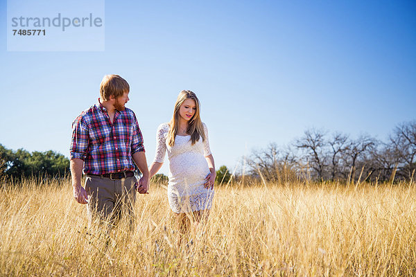 USA  Texas  Mann und schwangere Frau beim Gehen im Gras