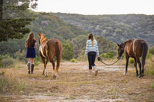 USA  Texas  Schwestern  die mit Quarterhorses am Berg spazieren gehen
