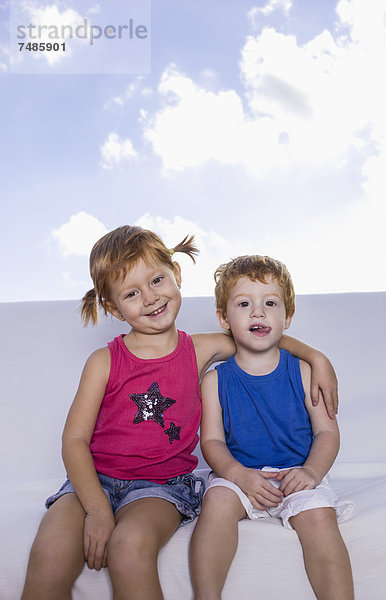 Spanien  Junge und Mädchen auf weißer Couch sitzend  lächelnd