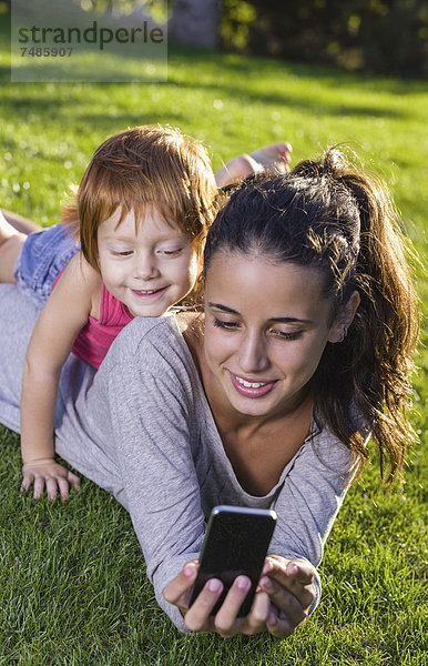 Spanien  Teenage Mädchen und Mädchen mit Smartphone auf Gras