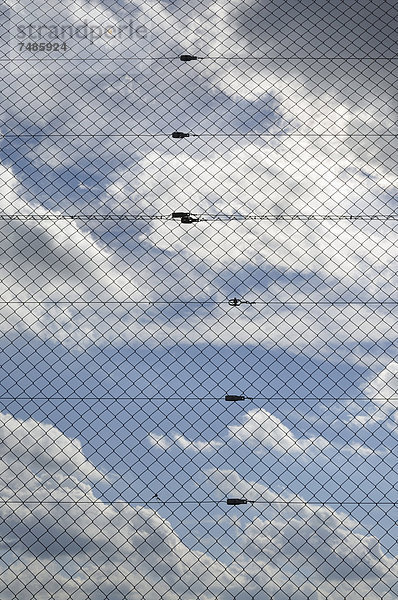 Deutschland  Bayern  Maschendrahtzaun gegen bewölkten Himmel