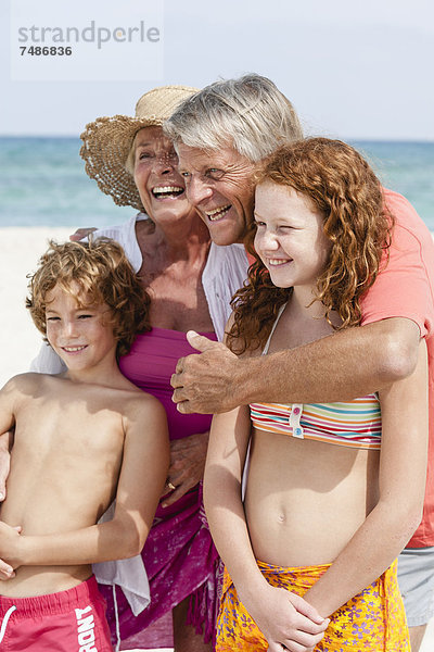 Spanien  Großeltern mit Enkelkindern  die Spaß am Strand haben  lächeln