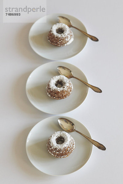 Miniaturkuchen mit Puderzucker und Löffel auf dem Teller