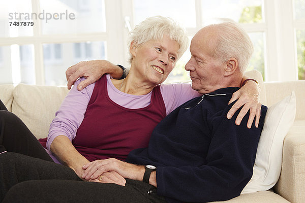 Deutschland  Düsseldorf  Seniorenpaar entspannt zu Hause  lächelnd
