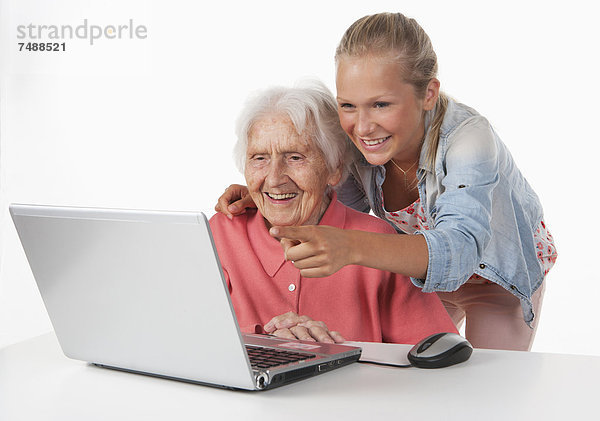 Seniorin und Teenagerin mit Laptop  lächelnd