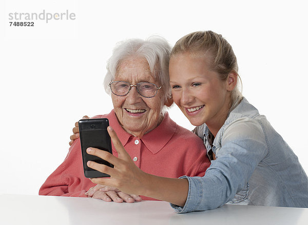 Seniorin und Teenagerin fotografieren sich selbst  lächelnd