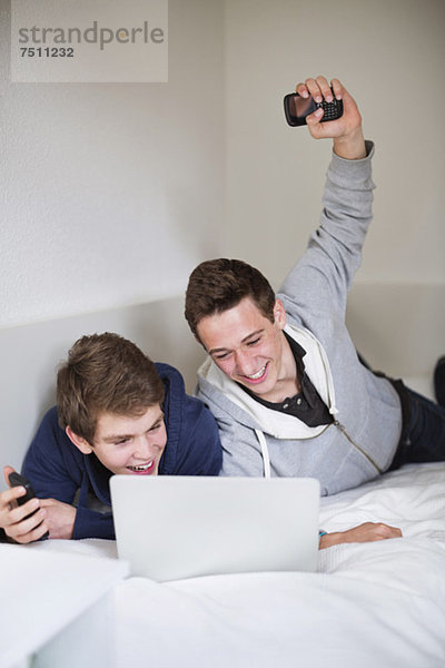 Aufgeregte Jungs feiern den Erfolg bei der gemeinsamen Nutzung des Laptops zu Hause.