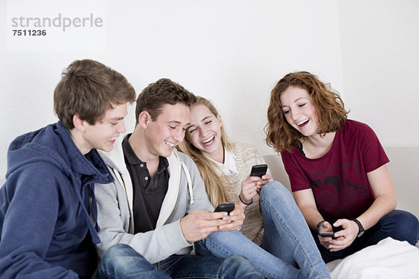 Glückliche junge Freunde  die zu Hause mit dem Handy telefonieren.