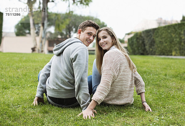 Portrait eines glücklichen jungen Paares  das zusammen im Park sitzt.