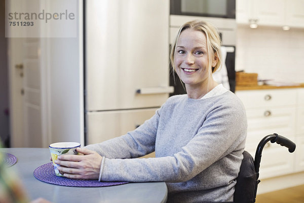 Porträt einer glücklichen behinderten Frau mit Kaffeetasse in der Küche