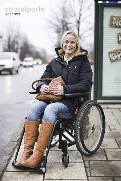 Porträt einer glücklichen behinderten Frau im Rollstuhl lächelnd im Freien