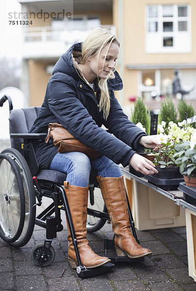 Behinderte Frau im Rollstuhl bei der Pflanzenwahl im Gartencenter