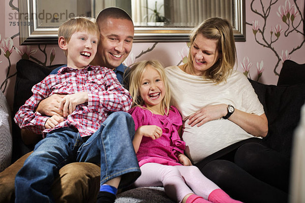 Porträt eines glücklichen Mädchens  das mit seiner Familie auf dem Sofa sitzt.