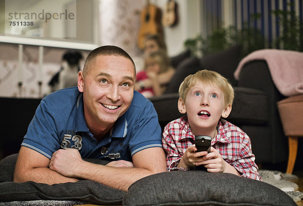 Überraschter kleiner Junge  der mit Vater zu Hause fernsieht.