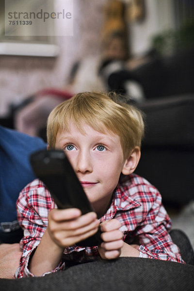 Kleiner Junge mit Fernbedienung  der zu Hause fernsieht.